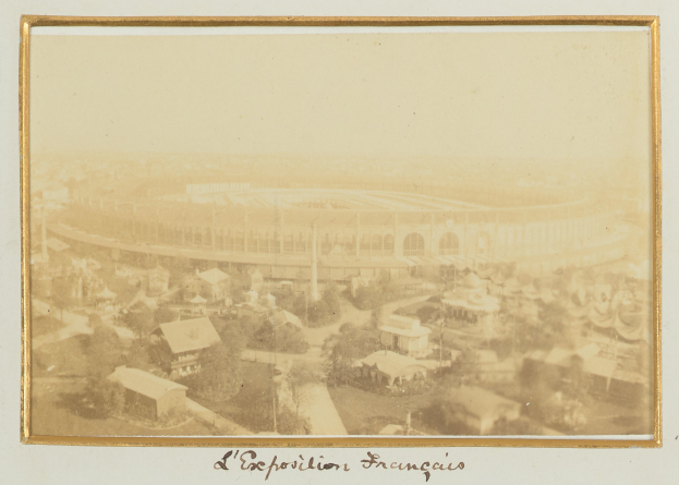 Altes Schwarz-Weiß-Foto eines Stadions in städtischer Umgebung mit umliegenden Gebäuden, Bäumen und Strommasten, mit Text am unteren Rand.