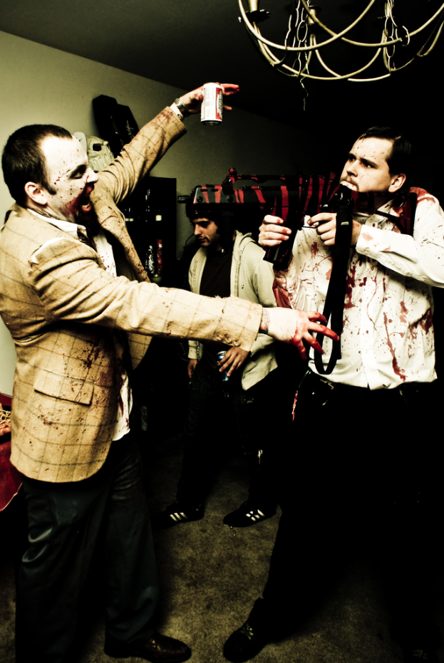 Eine Person auf der linken Seite des Bildes hält eine Dose, mit einer Wand und ein paar Leuten im Hintergrund.