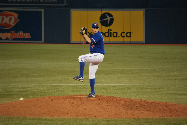 Ein Spieler steht auf dem Boden und hält einen Ball in der Hand, im Hintergrund eine große Fahne mit Text und Bildern.