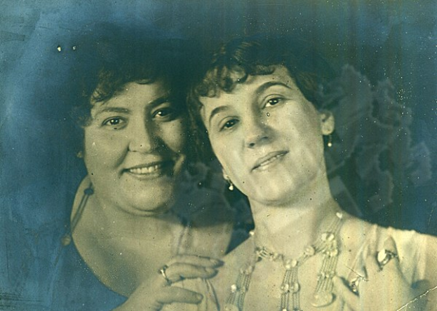 Zwei Frauen, die warm in eine alte Fotografie lächeln.