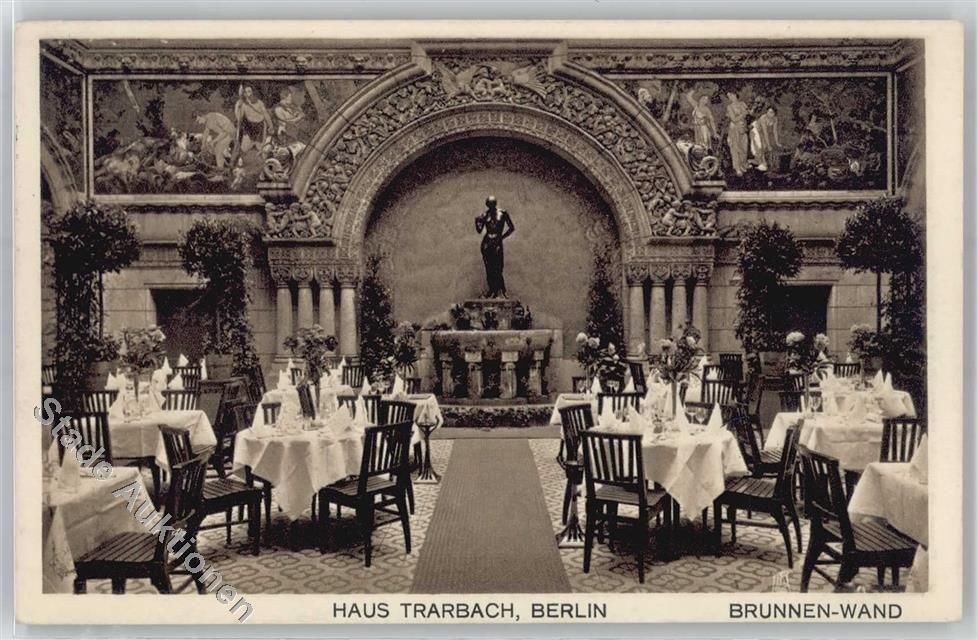 Schwarz-weißes Foto eines alten Berliner Restaurant-Interieurs mit Tischen, Stühlen, Blumenvasen, einer Statue, Skulpturen, Pflanzen und Text unten.