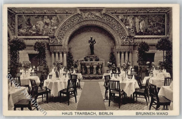 Schwarz-weißes Foto eines alten Berliner Restaurant-Interieurs mit Tischen, Stühlen, Blumenvasen, einer Statue, Skulpturen, Pflanzen und Text unten.