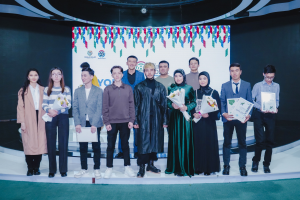 Gruppe von Menschen auf einer Bühne mit Blumensträußen und Urkunden, im Hintergrund ein "Jugend-Solar-Awards 2019"-Plakat.