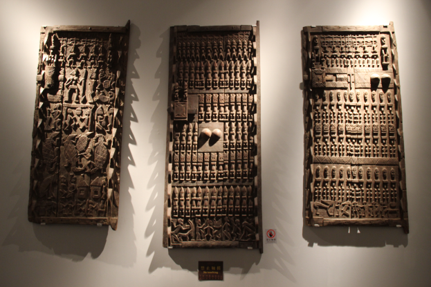 Drei hölzerne Tafeln mit kunstvollen Gravuren in einem Museum ausgestellt, mit einer Texttafel unten.