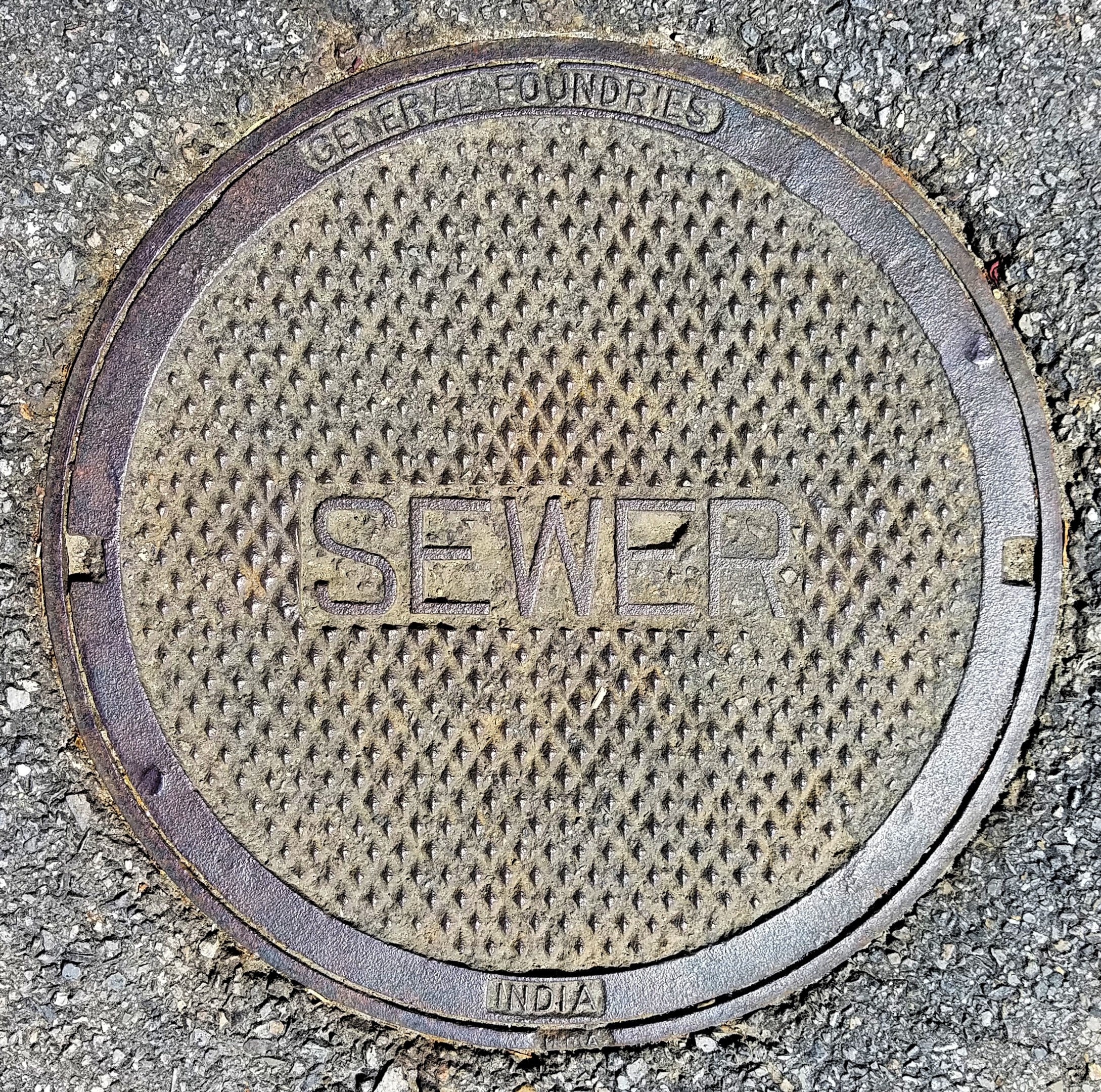 Metallschachtdeckel auf der Straße mit dem Wort "Kanal" geprägt.