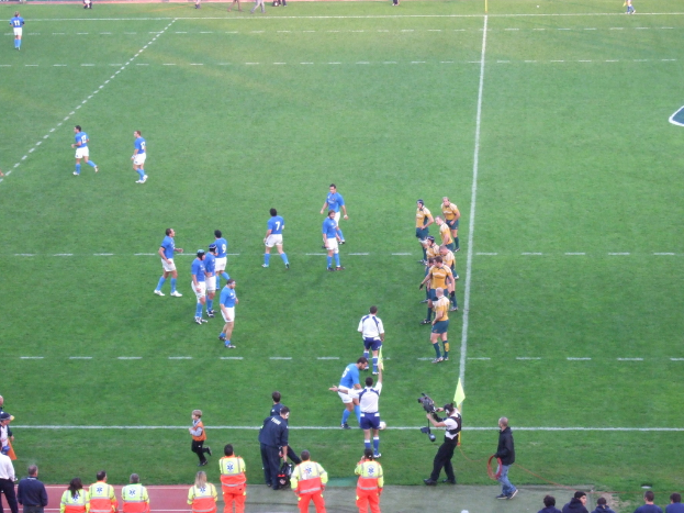 Eine Gruppe von Menschen auf einem Fussballfeld, eine Person hält eine Videokamera.