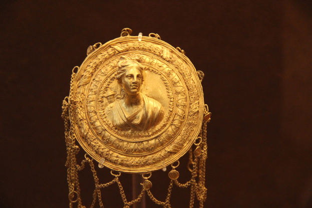 Goldene Medaille mit einer Frauengestalt auf dunklem Hintergrund, mit feiner und königlicher Verzierung.