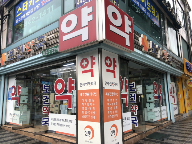 Außenansicht eines modernen Glaswand-Pharmagebäudes in Seoul, Südkorea, mit einer Tafel, die es als erstes Pharmageschäft in der Stadt identifiziert.