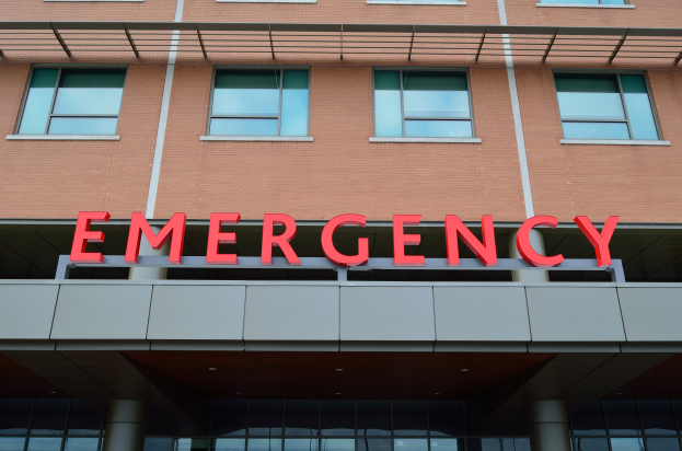 Ein Gebäude mit Glasfenstern, Säulen und einem sichtbaren roten Notaufnahme-Schild.