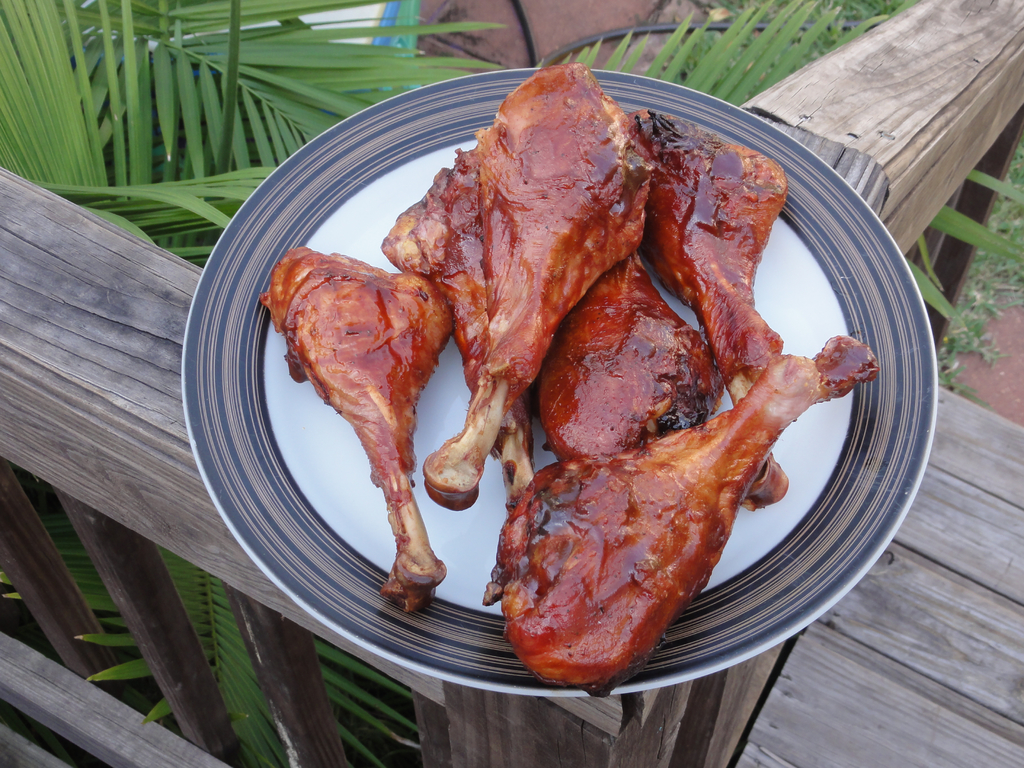 Ein Teller mit Fleisch darauf wird auf einem Holz Zaun mit Bäumen im Hintergrund platziert.