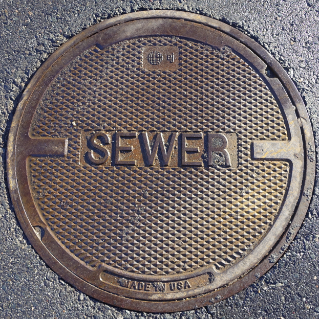 Ein Metall-Schachtobjekt auf der Straße mit dem Wort "Kanal" darauf.