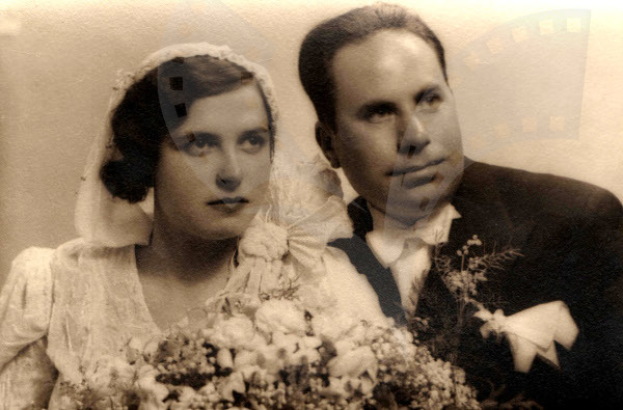 Ein Mann und eine Frau in festlicher Kleidung lächeln glücklich auf ihrer Hochzeit, wobei die Frau einen Blumenstrauß hält.