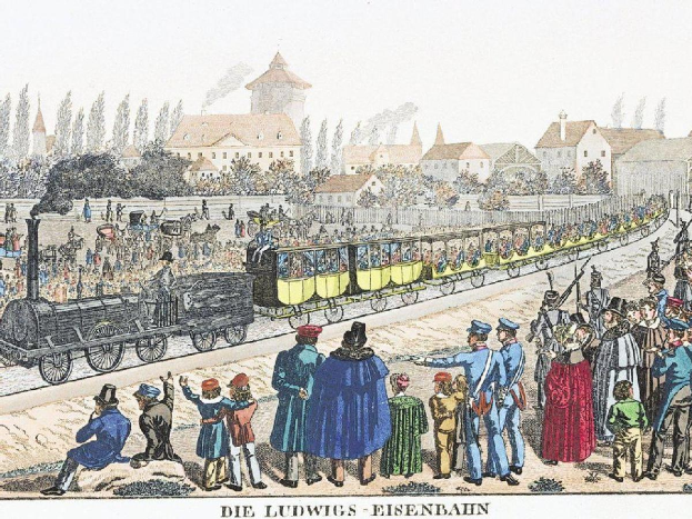 Eine Gruppe von Menschen steht um einen Zug auf den Schienen, einige sitzen im Zug und andere stehen auf dem Boden, in der Nähe von Gebäuden und Bäumen, mit Text unten lesend "Ludwigs-Eisenbahn, die erste Bahnstation in Deutschland".
