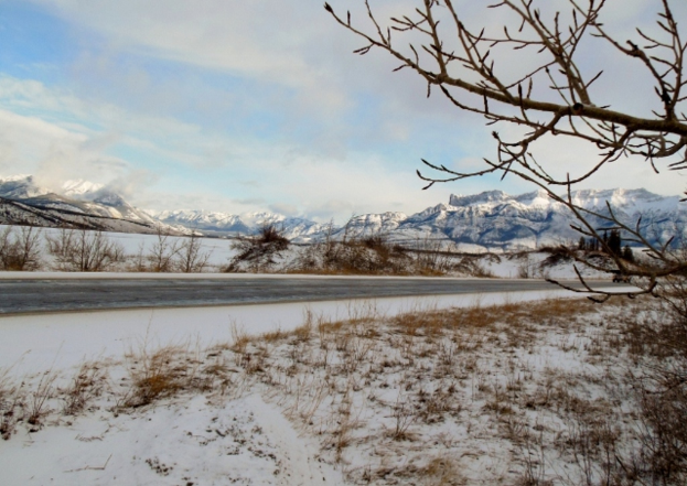 Eine von Schnee gesäumte Straße mit schneebedeckten Bergen im Hintergrund.
