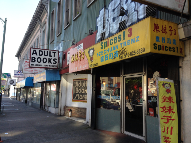 Eine belebte Stadtstraße mit Gebäuden, Fahrzeugen, Bäumen und einem Schaufenster mit der Aufschrift "Erwachsene Bücher".