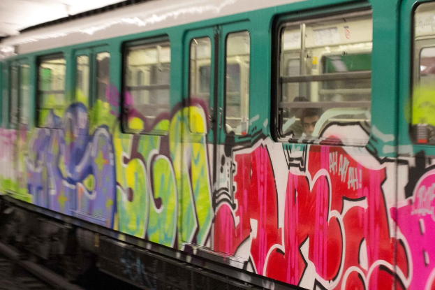 Ein Zug auf Bahngleisen mit zwei Personen darin und Graffiti an seiner Außenseite.