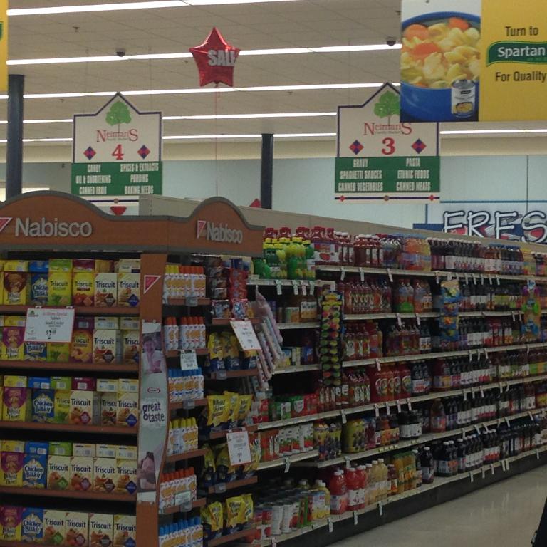 Ein Supermarktinneres mit sichtbaren Lebensmitteln, Deckenleuchten und Schildern.