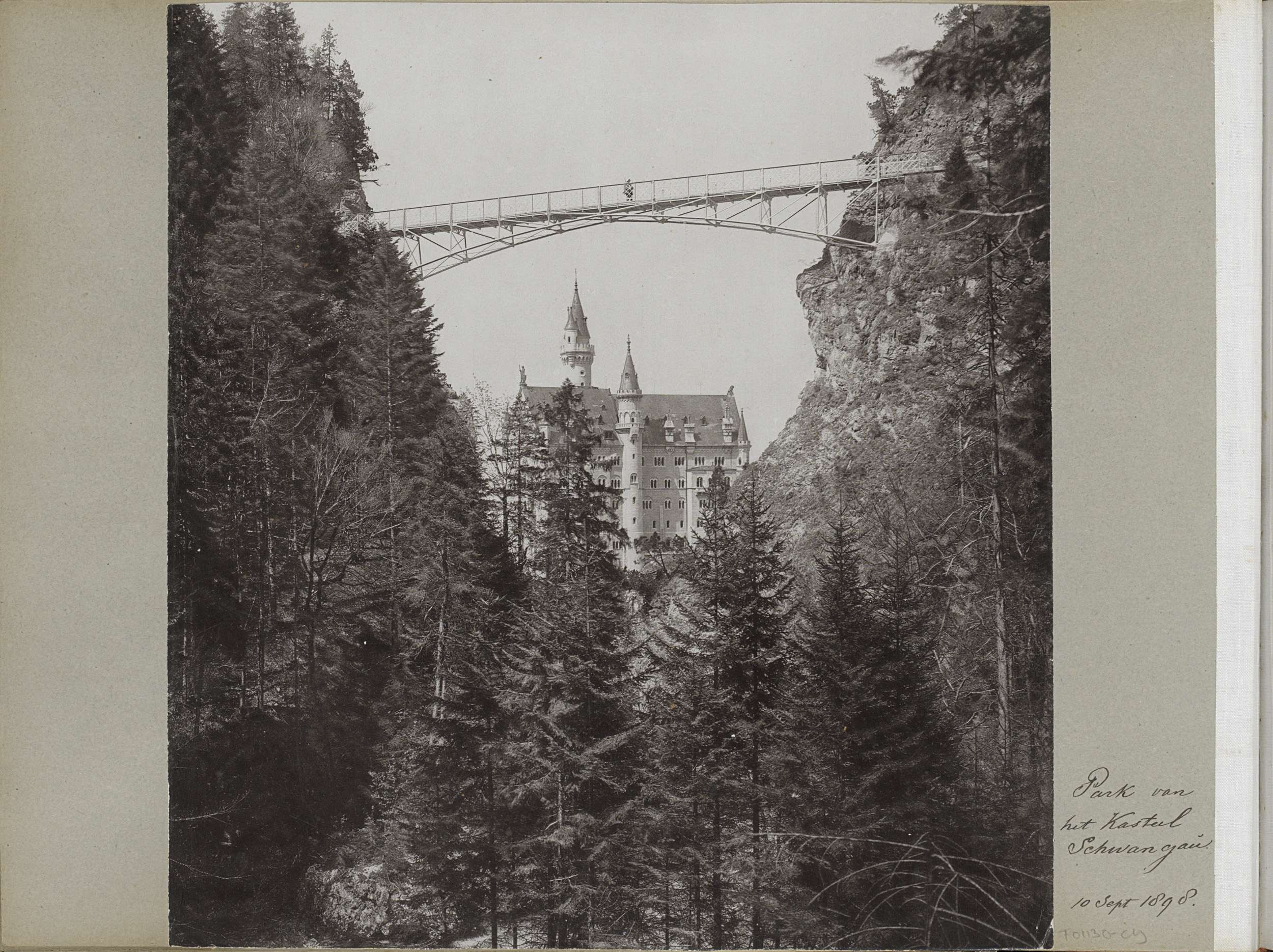 Ein Schwarz-Weiß-Foto von Schloss Neuschwanstein in Deutschland mit einer Brücke im Vordergrund, umgeben von Bäumen und Text auf der rechten Seite.