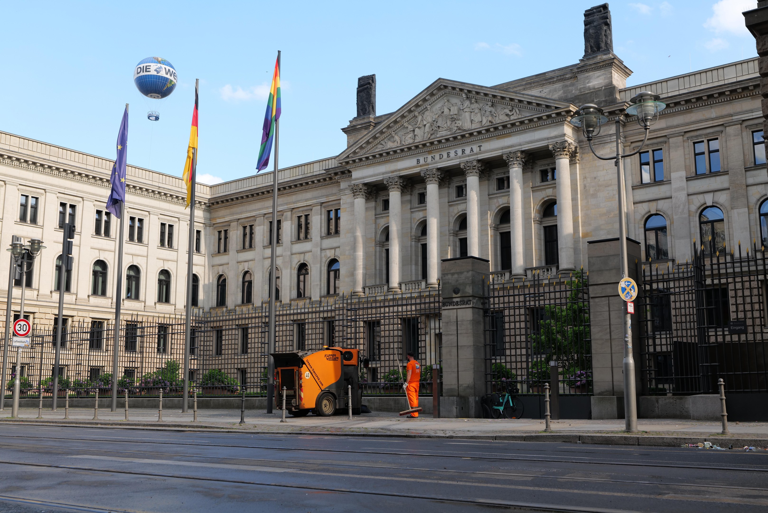 Großes modernes Gebäude mit zahlreichen Fenstern, identifiziert als der Bundestag in Berlin, Deutschland, umgeben von Straßeninfrastruktur und Fussgängern, unter einem bewölktem Himmel.