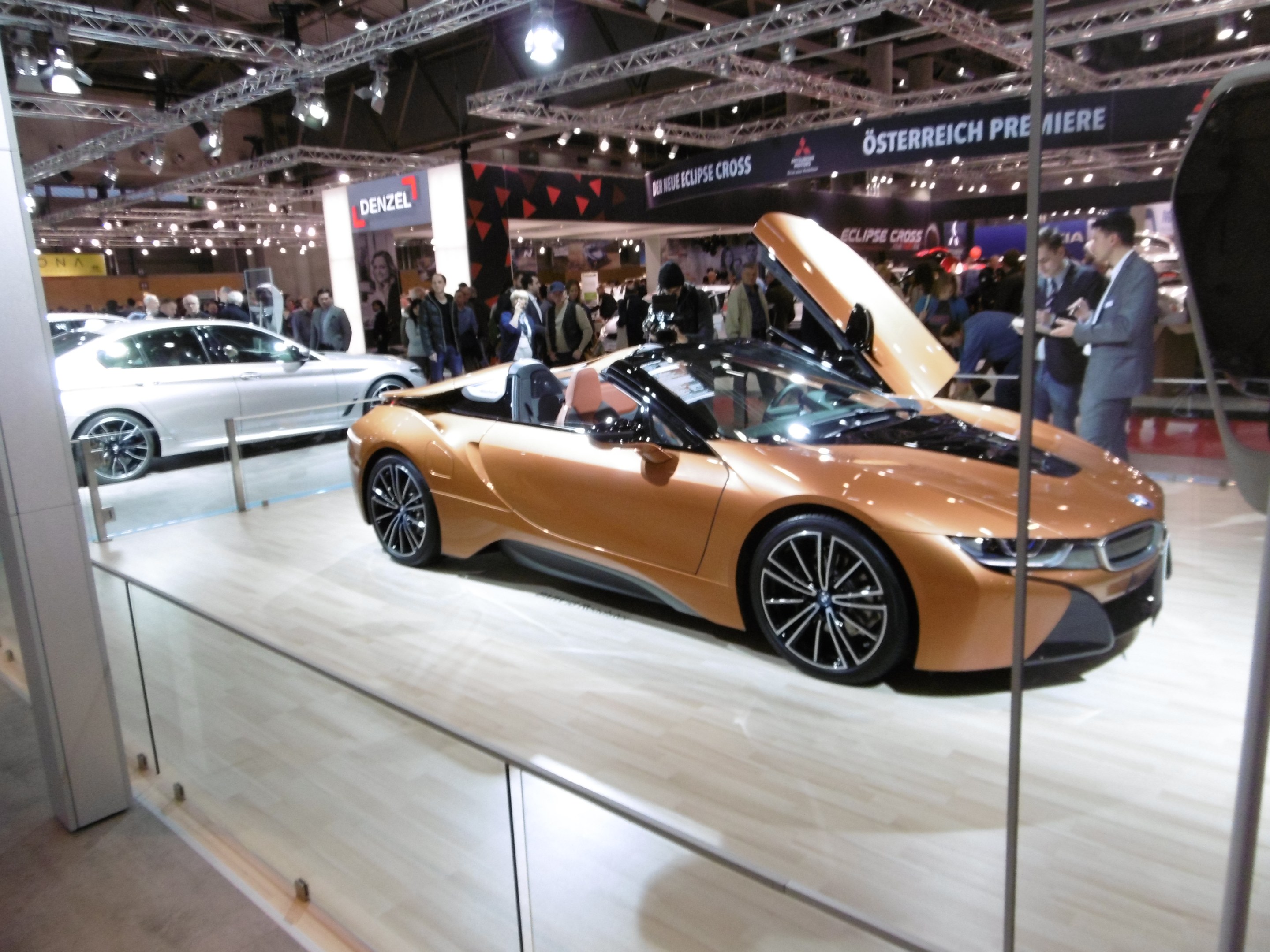 Schwarzer BMW i8 Roadster mit glänzender Lackierung und Chromakzenten, präsentiert auf der IAA in Frankfurt, umgeben von formell gekleideten Besuchern.