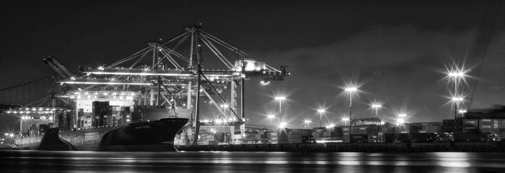 Ein Schiffbau mit Metallkonstruktionen, Laternenmasten, Containern und Schiffen.