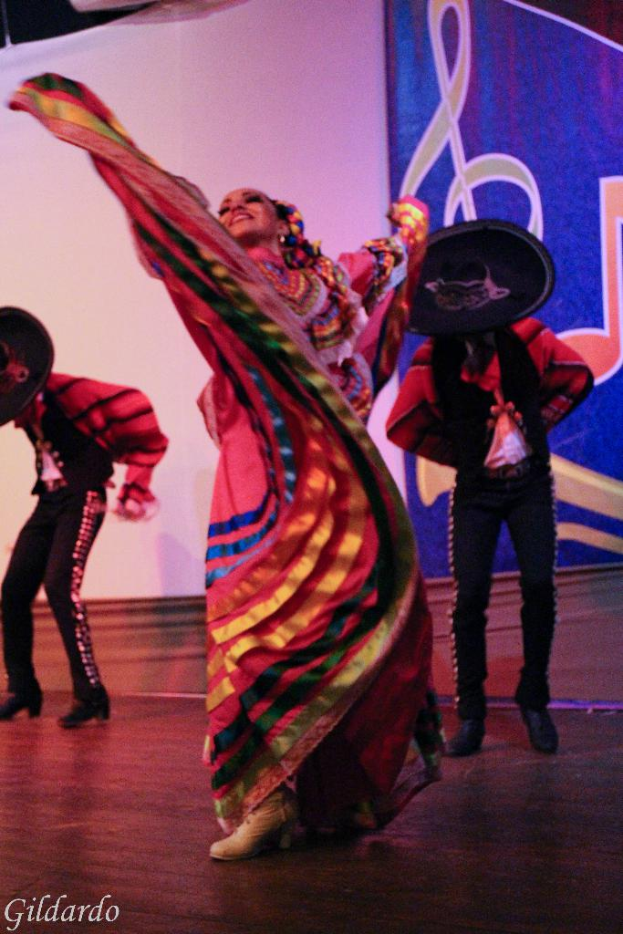 Menschen auf einer Bühne in Kostümen, mit einem Vorhang mit einem Bild im Hintergrund.