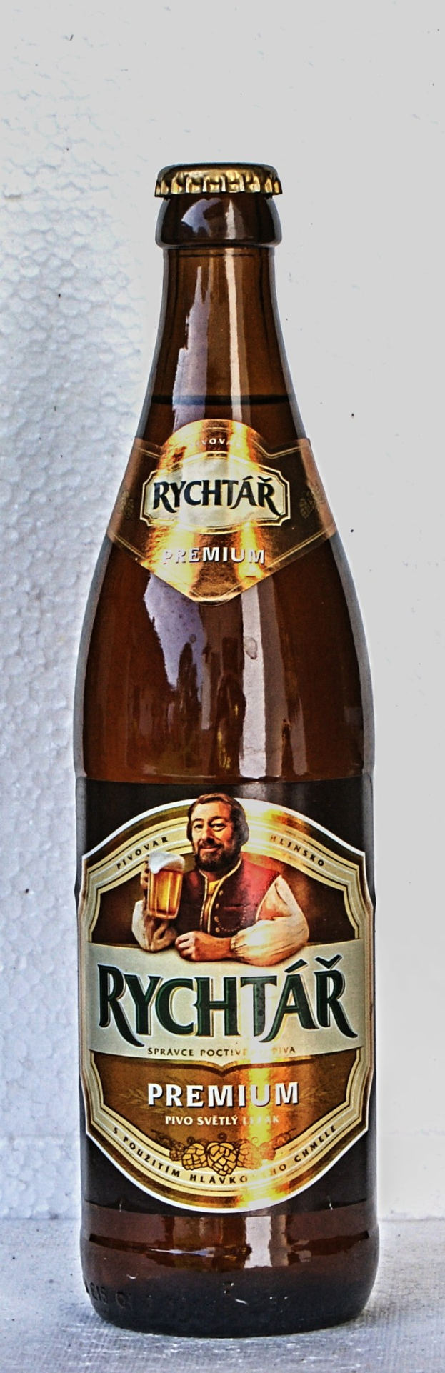 Eine Flasche Rychtar Premium-Bier mit einem Etikett, das eine Person und Text zeigt, auf einem Tisch.