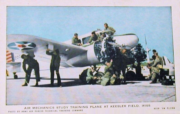 Eine Gruppe von Menschen steht um ein Flugzeug auf einer Landebahn mit einem klaren blauen Himmel im Hintergrund, und ein Text am unteren Rand, der 'Luftmechanik-Studium Trainingsebene auf Keesler Field, Miss.' lautet