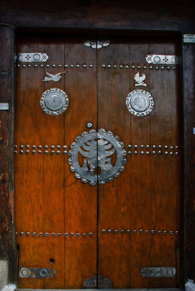 Eine hölzerne Tür mit einer Metallgestaltung darauf.