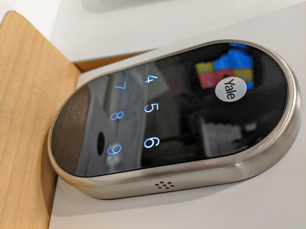 Ein Close-up einer Yale Smart Lock-App auf einem weißen Tisch mit einem hölzernen Objekt links daneben.