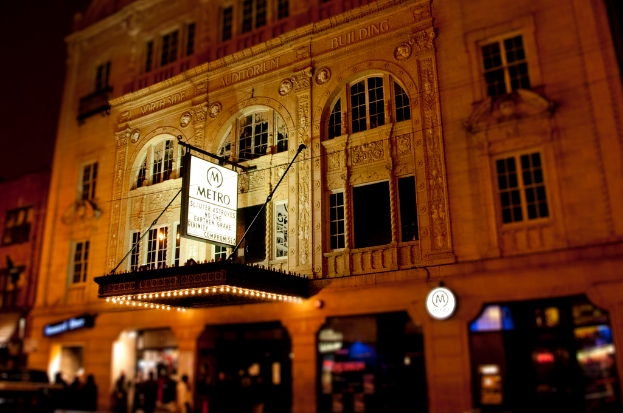 Ein gelbes Gebäude mit Geschäften und einem weißen Schild, auf dem "Metro" steht.