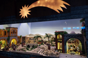 Eine Krippe in einem Museum mit Menschen, Tieren, Häusern, Bäumen und anderen Gegenständen, mit einer beleuchteten Hintergrundatmosphäre.