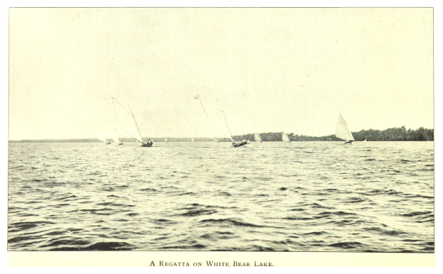 Eine Regatta auf dem White Bear Lake mit Booten auf dem Wasser, Bäumen im Hintergrund und Text unten.