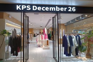 Das Innere eines KPS-Geschäfts am 26. Dezember in Singapur, mit Kleidung an Bügeln, bekleideten Schaufensterpuppen, Topfpflanzen, Glaswänden, Deckenleuchten und einem Schild mit Text, mit dem Boden unten.