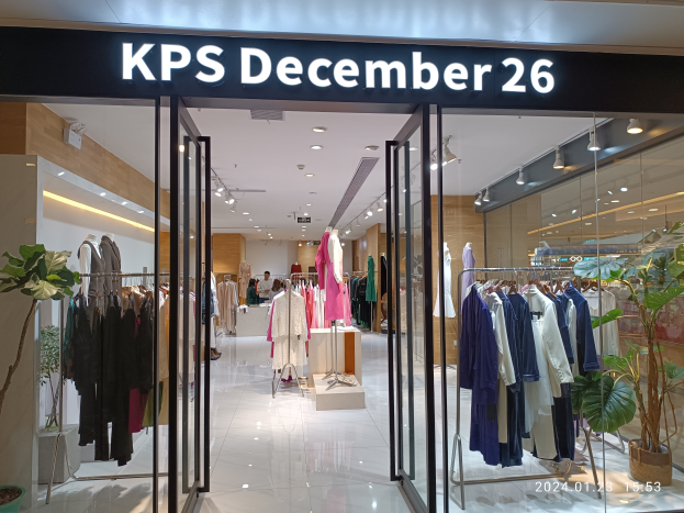 Das Innere eines KPS-Geschäfts am 26. Dezember in Singapur, mit Kleidung an Bügeln, bekleideten Schaufensterpuppen, Topfpflanzen, Glaswänden, Deckenleuchten und einem Schild mit Text, mit dem Boden unten.
