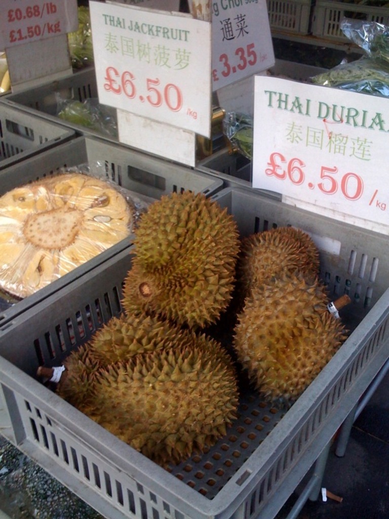 Fruits in trays with price boards in the background.