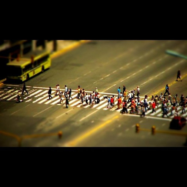 Eine Straße mit Menschen, einem Bus, Ampeln und einem Auto auf der rechten Seite.