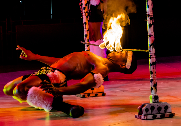 Eine Person schaut auf ein Feuer, das auf einer Stange an Pfählen ist.