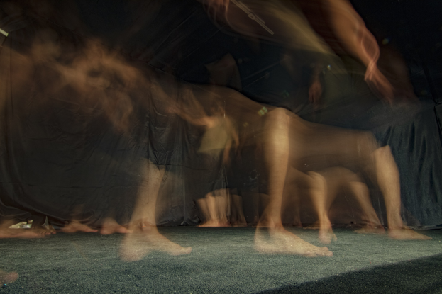 Gruppe von Menschen auf einer Bühne mit schwarzem Tuch-Hintergrund, Bild leicht unscharf.