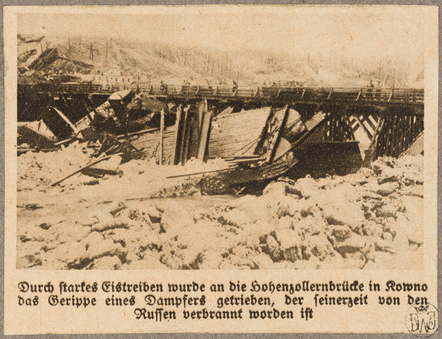 Ein altes Schwarz-Weiß-Foto einer abgerissenen Brücke mit ein paar Menschen darauf und Text unten.