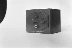 Ein Schwarz-Weiß-Foto einer rechteckigen Safe-Box auf einer weißen Oberfläche, mit einem Griff oben, einem Schloss vorne und einem Schlüsselloch in der Mitte.