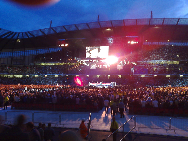 Eine Veranstaltungslocation mit Menschen, Bühnenlicht und Projektionsschirm.