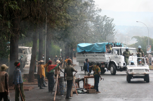 Arbeiter f√ľhren Aufgaben neben einer Stra√Ÿe mit einem Lastwagen durch, auf dem eine gro√üe Menge steht, w√§hrend Beamte in einem Fahrzeug in der N√§he fahren, umgeben von B√§umen und Stra√Ÿenlaternen.