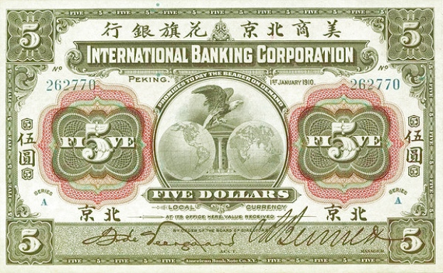 Ein alter Fünf-Dollar-Schein der International Banking Corporation mit dem Porträt eines Mannes im Anzug und Krawatte, darüber in fetter schwarzer Schrift der Name der Corporation auf einem leicht abgenutzten hellblauen Hintergrund.
